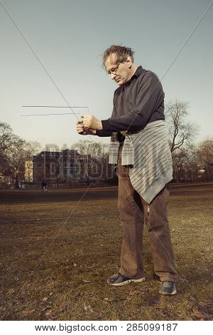 Man In Ugly Style Dress Practicing In Dowsing With Rods