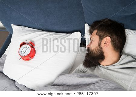 Man Bearded Hipster Sleepy Face In Bed With Alarm Clock. Problem With Early Morning Awakening. Get U