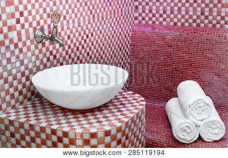 Traditional Turkish Hamam With Stone Walls, Sink And Stack Of  Towels