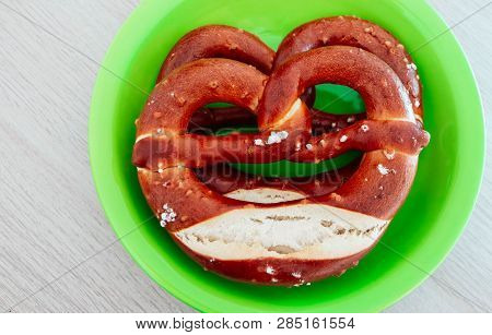 Two Traditional Bavarian Pastry Bretzes, Beer Snack On A Green Plate, Wooden Background. German Salt