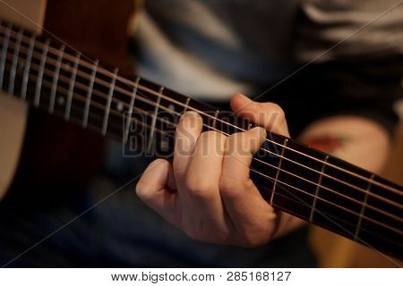 A Person Performs A Melody On An Acoustic Guitar, Holding A Hand Chord On The Fretboard