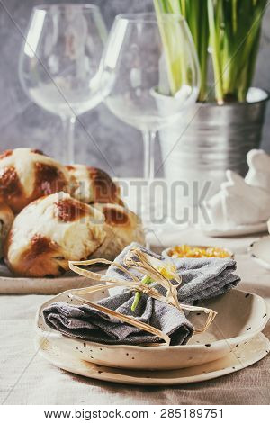 Easter Table Setting With Plate Of Hot Cross Buns, Narcissus Flowers, Wine Glass On Table With Linen
