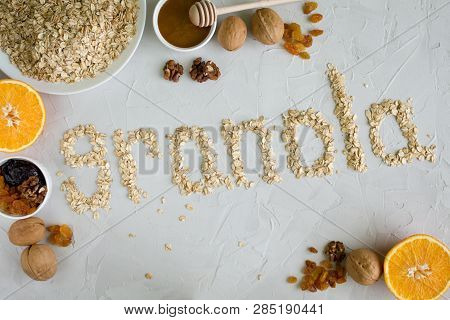 Ingredients For Granola. The Word Granola Made From Oat Flakes On A Grey Background