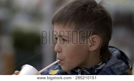 Boy Drinks A Milkshake At A Cafe Outdoors