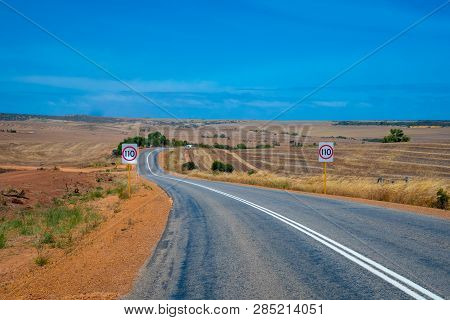 Australian Bush Road Leading Through Dry Landscape And Farmland With Speed Limit 110 Kph