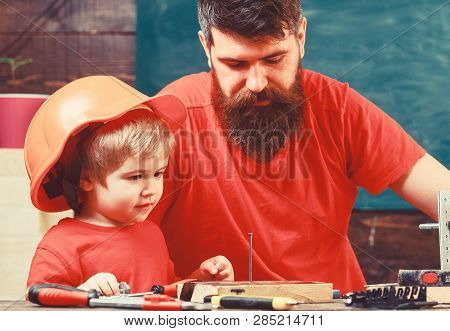 Workshop Concept. Boy, Child Busy In Protective Helmet Learning To Use Hobnails, Pins With Dad. Fath