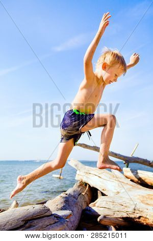 Happy Child Jumping On The Summer Beach
