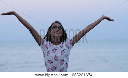 Young Girl Hands Up On The Beach Near The Ocean In The Evening.