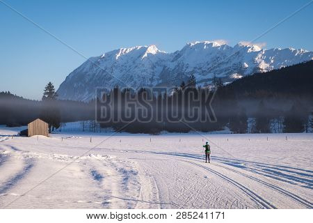 Woman Running Cross-country Skiing In Bad Mitterndorf With Nice View To Mountain Grimming On A Sunny