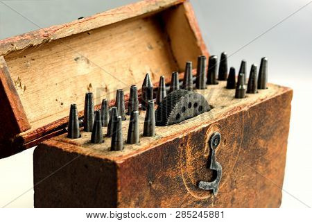 A Vintage Circular Round Corner Punches Set With An Anvil With Apertures In A Wooden Box. On A Gray 