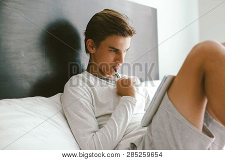16 years old teenage boy prepare for exams while relaxing on couch in his room