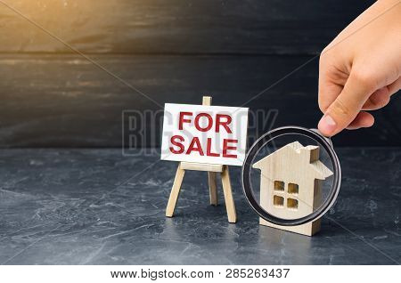 Magnifying Glass Is Looking At The Wooden House Stand With A Sign For Sale. Selling A House Or Apart