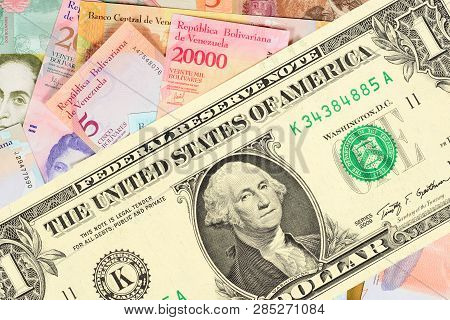 Large One-dollar Bill Against The Background Of Many Small Venezuelan Banknotes. The Concept Of Hype