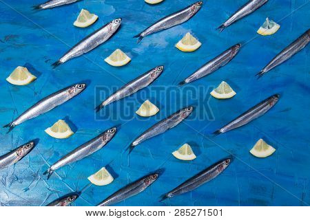 Fish Pattern. Anchovies In The Shape Of A Circle On A Black Stone On A Blue Sea Background. Seafood.
