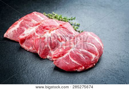 Traditional German raw pork cheeks with hers as closeup on a black board 