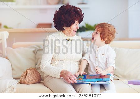 Portrait Of Beautiful Mature Woman (80 Years Old) With Her Great-grandson At Home, Reading Education