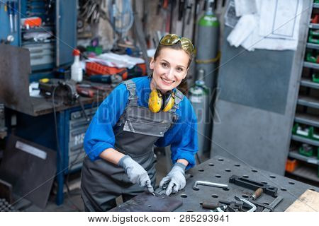 Sideview of worker woman marking piece of metal being absorbed in her work