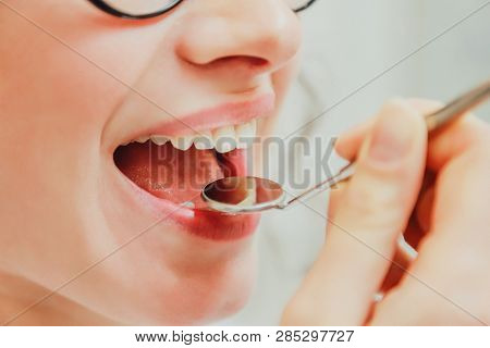 A Young Attractive Girl In A Review At A Dentist. Beautiful Girl Opening Her Mouth Sits On A Dental 