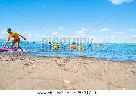 Mount Maunganui New Zealand - February 10 2019:  Children Carrying Colorful Paddle Boards Developing