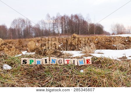 A Colorful Inscription Spring Made Up Of Wooden Cubes Stands On A Plowed Field In Spring. The Beginn