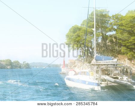 Sailing Catamaran Sails Along The Rocky Green Coast Past The Red Literary Sign - The Fairway Lightho