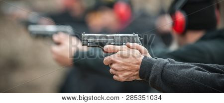 Close-up Detail View Of Shooter Hold Handgun In Row Group Of People On The Shooting Range