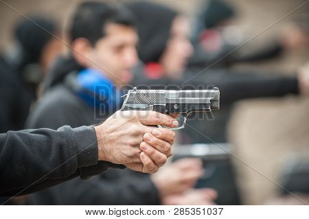 Close-up Detail View Of Shooter Hold Handgun In Row Group Of People On The Shooting Range