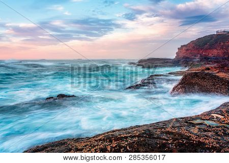 Standing On The Edge Of The Coastal Rock Platform Watching The Waves Breaking Upong The Rocky Coastl