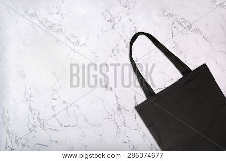 Closeup Of Black Tote Bag On White Marble Texture. Blank Reusable Shopping Bag On Marble Background.