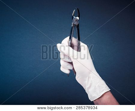 Hand in glove holding medical flatterns on dark blue background