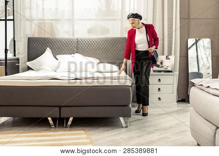Bewitching Fashionable Aging Woman Selecting New Grey Bed In Store