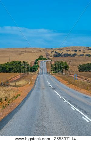 Australian Bush Road Leading Through Dry Landscape And Farmland With Empty Road