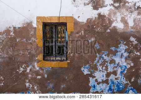 Wall Of An Old House With Peeled Off Paining Of The Facade, With Blue And White Color. Yellow Frame 