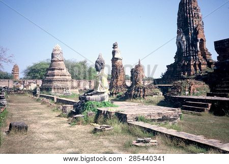 A Sculpture Of The Buddha Sits Among The Ancient Ruins Of Wat Phra Mahathat In Ayutthaya, Thailand.