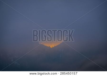 Last Minutes Of Sunset Behind The Forest On A Very Foggy Evening On A Winterday In Styria, Austria