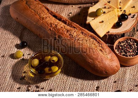 Fresh Bread Baguette With Olive Oil, Olives. Cheese And Rosemary On Wooden Background. Teasty Breakf