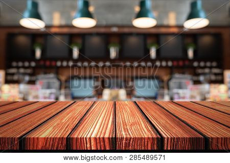 Empty Wooden Board Top Table In Front Of Counter Coffee Shop Blurred Background. Perspective Wood In