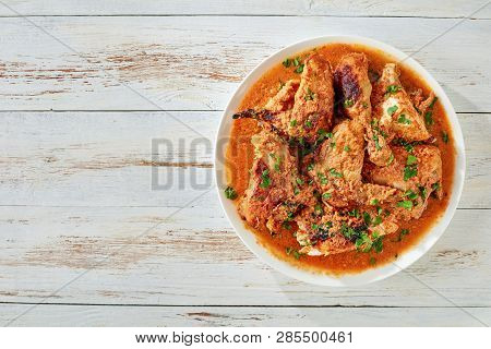 Chicken Stewed In Creamy Spicy Coconut Gravy, Kuku Paka, Served On A White Plate On An Old Wooden Ta