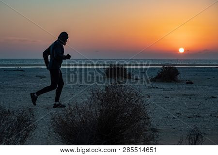 A Man Engaged In Running. The Athlete Runs Along The Seashore At Sunset. Trail Running. Mangystau Pe