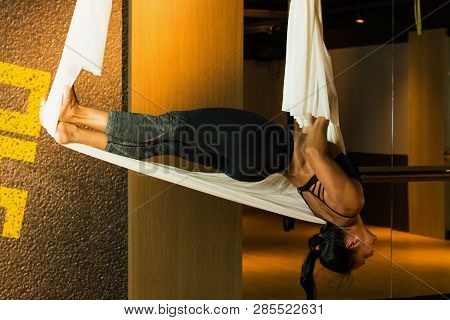 Young Woman Practicing Aerial Yoga In Fitness Studio