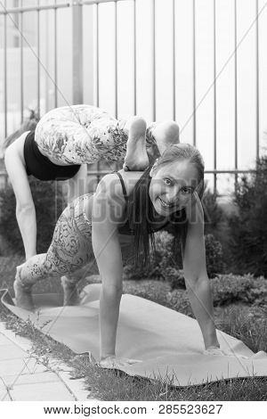 Two Young Women Practicing Acro Yoga Outdoors