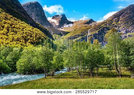 Waterfall, River And Green Trees On The Way To Briksdal Or Briksdalsbreen Glacier In Olden, Norway