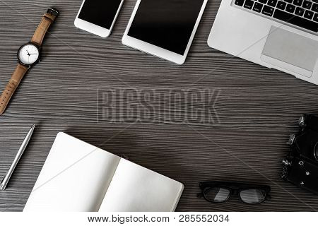 Business Work Desk With Laptop, Phone, Digital Tablet Camera Notebook Pen Glasses And Watch On Dark