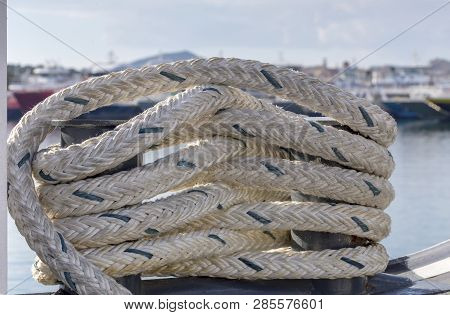 Marine Mooring Devices. Mooring Rope On The Ship Hanging Close-up Against The Coastline