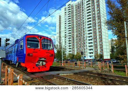 The train quickly goes past the multi-storey residential building, the blue sky.