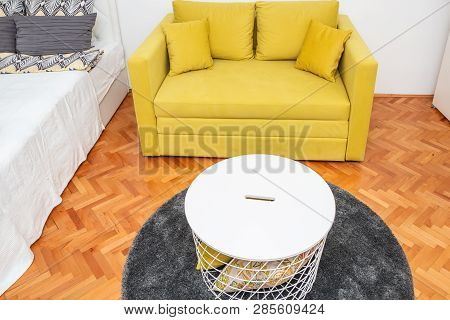 Modern Hotel Bedroom Interior With Yellow Two-seat Sofa, Double Bed And Tabouret Or Table.
