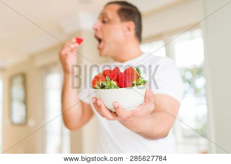 Middle age man eating straweberry at home