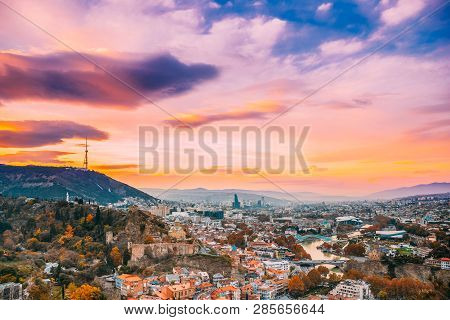Tbilisi, Georgia. Georgian Capital Skyline Cityscape. Top View Of Famous Landmarks In Sunsset Lights