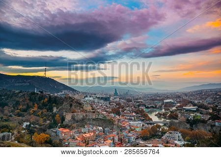 Tbilisi, Georgia. Georgian Capital Skyline Cityscape. Top View Of Famous Landmarks In Sunsset Lights