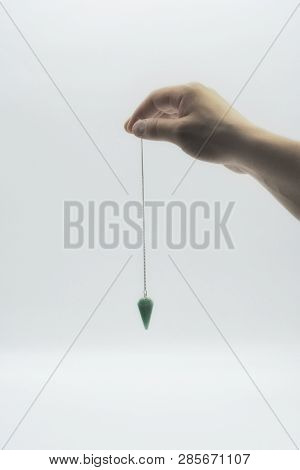 Pendulum Dowsing On An Isolated White Background With A Turquoise Crystal.